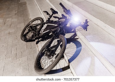 A Bicycle Parked At Night On A City Street With A Light Lamp On