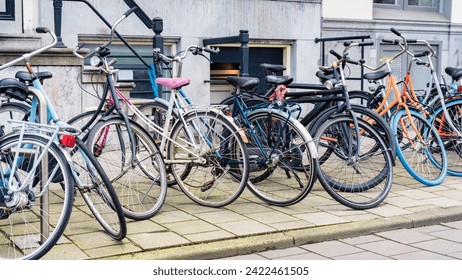 Bicycle parking in the city. An urban cityscape with bicycles. Bicycle parking along a street in Amsterdam. Old walking bikes parked carelessly outside an old city building in Netherlands.