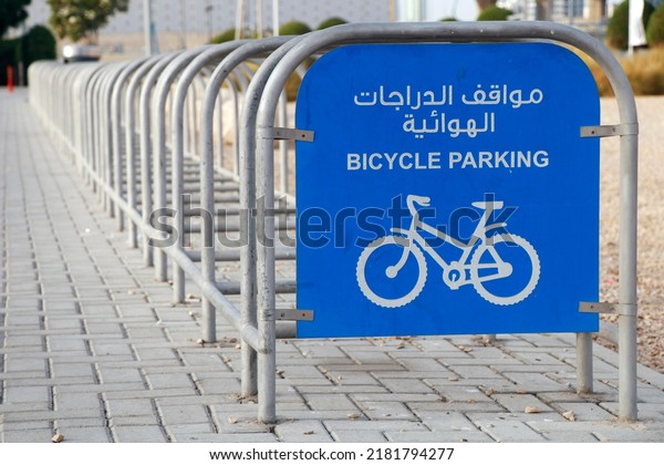 bicycle parking station in street side with\
sign board in english and arabic\
letter