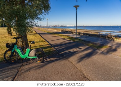 Bicycle Path Along The Embankment In Tallinn And A Green Electric Bike.