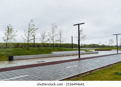 Bicycle path in the city park, bench for relaxation, landscape design of urban space place for walking, mowed lawn green grass, lamppost designer. High quality photo