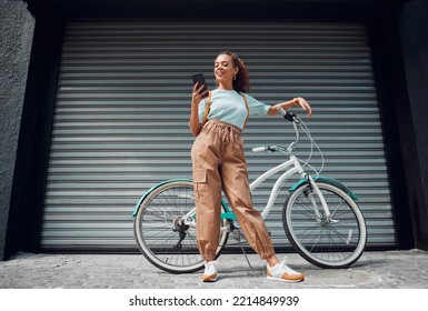 Bicycle, phone and black woman in city, street or urban road outdoors. Bike, travel and happy female from South Africa on 5g mobile tech, internet browsing or social media, web or online surfing. - Powered by Shutterstock