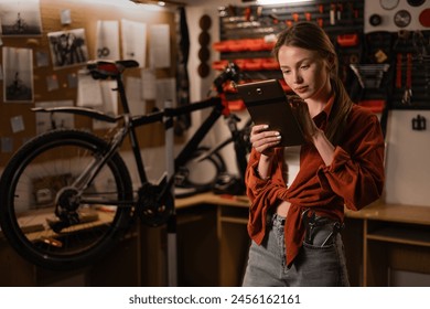 bicycle repair. Blonde woman using a digital tablet in a bicycle repair shop. Copy space - Powered by Shutterstock