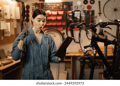 bicycle repair concept. Brunette woman using a digital tablet in a bicycle repair shop. Copy space - Powered by Shutterstock