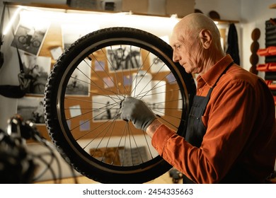 Bicycle repair in workshop, old man holding bike wheel. Copy space - Powered by Shutterstock