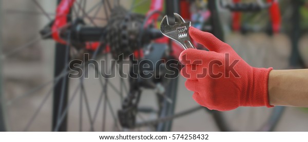Bicycle repairing,Hand of Bicycle technician auto\
mechanic with a wrench working in garage. service in auto repair\
station.vintage tone,for\
banner