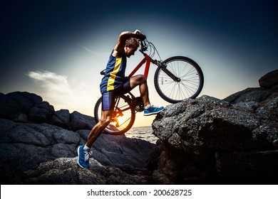 Bicycle rider crossing rocky terrain at sunset - Powered by Shutterstock