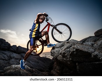 Bicycle Rider Crossing Rocky Terrain At Sunset