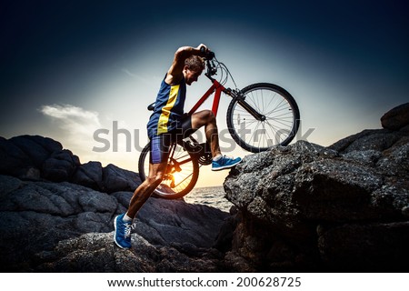 Bicycle rider crossing rocky terrain at sunset