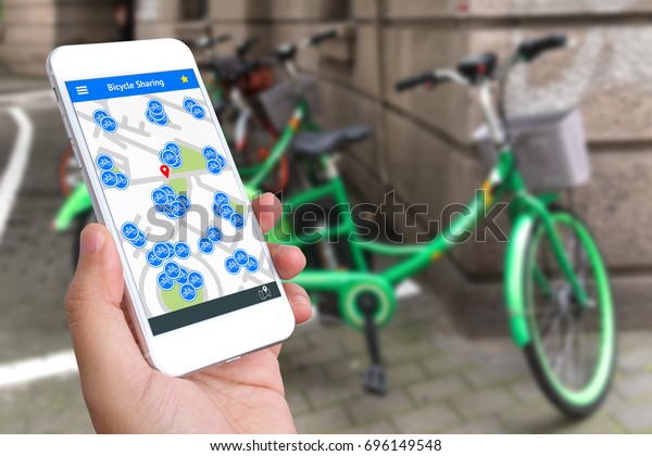 Bicycle sharing service or rental\
technology concept. Sharing economy and collaborative consumption.\
Customer hand using mobile phone to find bicycle for\
ride.