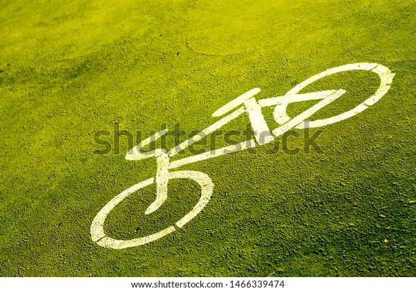 bicycle sign\
stencilled with white paint on a bright green pavement indicating a\
designated area for\
cycling