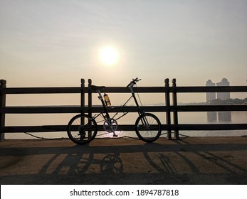 Bicycle silhouette beachside when sun goes down with cityskape backround