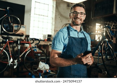 Bicycle, small business and phone of man, smile and garage of mechanic, apron and equipment. Portrait, owner and person with service, maintenance and tools for bike, technician or working with mobile - Powered by Shutterstock