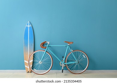 Bicycle and surfboard near color wall in room - Powered by Shutterstock