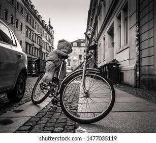 Bicycle With Teddy Bear Parked On Side Walk In An Urban Street With Historic Townhouses In A Low Angle View