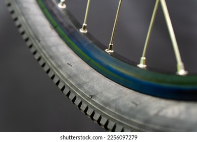 Bicycle tire and wheel close-up on a black background. Abstract background of a wheel in a bicycle workshop. Dirty old worn-out tire.