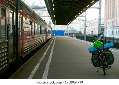 A Bicycle With Tourist Equipment On The Station Feather. The Train Is Preparing To Leave. Tourist And Solo Travel Concept. Road Trip, Staycations And Back To Basics Idea.