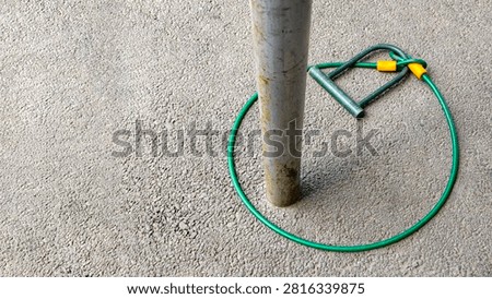 Bicycle u lock and cable lock securing itself around a metal pole on asphalt, ironically depicting a concept of failed security, vulnerability, inadequate protection, and misplaced trust