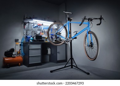 Bicycle workshop for repairing bicycles. Bicycle hanging on a repair stand in the background of a workbench with professional tools. Bicycle service. - Shutterstock ID 2203467293
