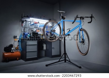 Bicycle workshop for repairing bicycles. Bicycle hanging on a repair stand in the background of a workbench with professional tools. Bicycle service.