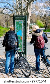 Bicyclists In Central Park, New York City, Stop To Check A Map Kiosk