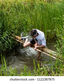 Biddinghuizen, The Netherlands - June 23, 2018: Man During A Mud Run (mudraise, Charity) In The Mud And In The Water Climbing A Tree Trunk.