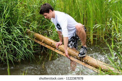 Biddinghuizen, The Netherlands - June 23, 2018: Man During A Mud Run (mudraise, Charity) In The Mud And In The Water Climbing A Tree Trunk.