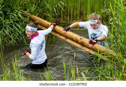 Biddinghuizen, The Netherlands - June 23, 2018: Girls During A Mud Run (mudraise, Charity) In The Mud And In The Water Climbing A Tree Trunk.