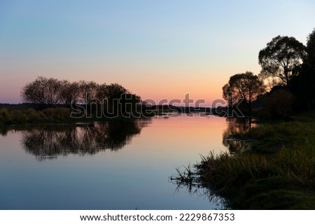 Biebrza river at sunset, reflection in the water, silhouettes of trees reflecting in the calm water of the river. 