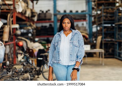 Big African American Woman Modeling. Old Machine Auto Parts In Warehouses. Auto Mechanic Car Service, Repair And Maintenance Concept. Used Car-auto Mobile Spare Parts