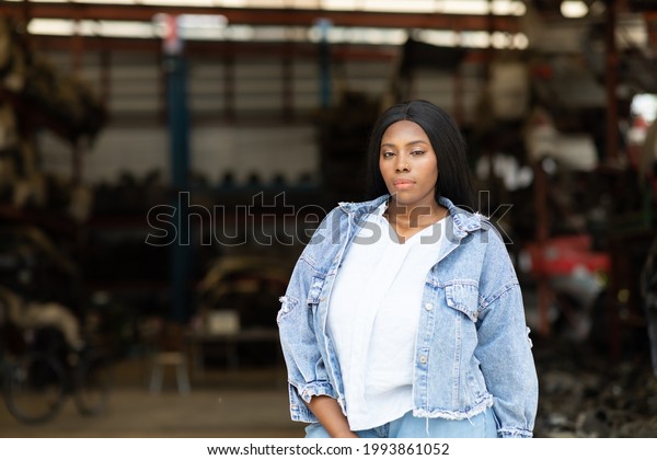 Big african\
american woman modeling. Old Machine auto parts in warehouses. Auto\
mechanic car service, repair and maintenance concept. used car-auto\
mobile spare parts