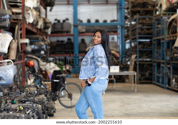 Big african\
american woman modeling. Old Machine auto parts in warehouses. Auto\
mechanic car service, repair and maintenance concept. used car-auto\
mobile spare parts