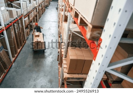 Big area, going with boxes, distant view. Foreman is in the storehouse, shipping distribution business.