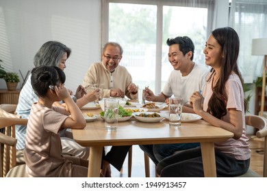 Big Asian Happy Family Spend Time Having Lunch On Dinner Table Together. Little Kid Daughter Enjoy Eating Food With Father, Mother And Grandparents. Multi-Generation Relationship And Activity In House