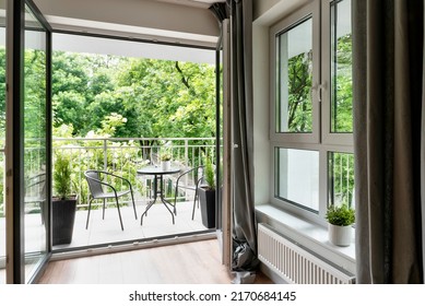 Big Balcony Window In New Apartment With Beautiful View On Green Nature And Table With Chairs. Modern Building With Patio.