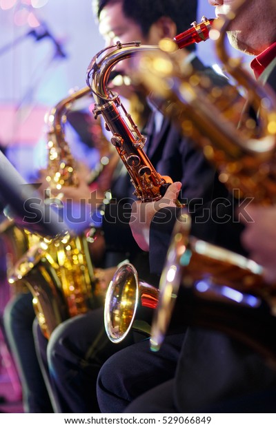 Big Band\
saxophone section. Candid view of a row of saxophone players in mid\
performance during a big band\
rehearsal.