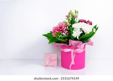 Big beautiful bouquet of  various natural flowers in a pink box near gift. White background. Greeting card for birthday, mother's day, women's day or other occasion. Copy space. - Powered by Shutterstock