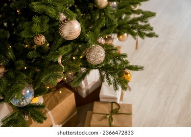Big beautiful christmas tree decorated with beautiful shiny baubles and many different presents on wooden floor. White wall background with copy space. - Shutterstock ID 2366472833