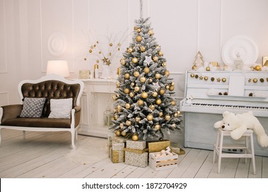 Big beautiful Christmas tree with gifts in a white decorated hall for the New Year. Piano