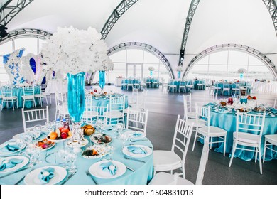 
Big Beautiful Decorated Restaurant At The Wedding, Wedding In Blue And White Colors, Orchids Flowers In Vases With Blue Water 