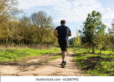 Big belly man jogging - exercising, doing cardio in the park - slightly overweight  loosing weight - Young overweight man running outdoors - Fat man running