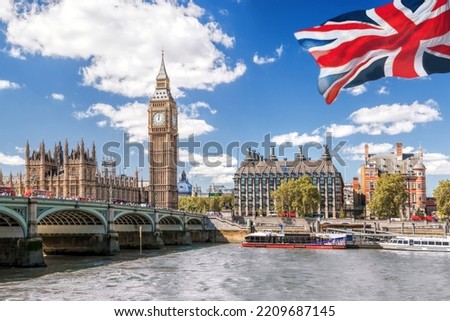 Big Ben with bridge over Thames and flag of England against blue sky in London, England, UK