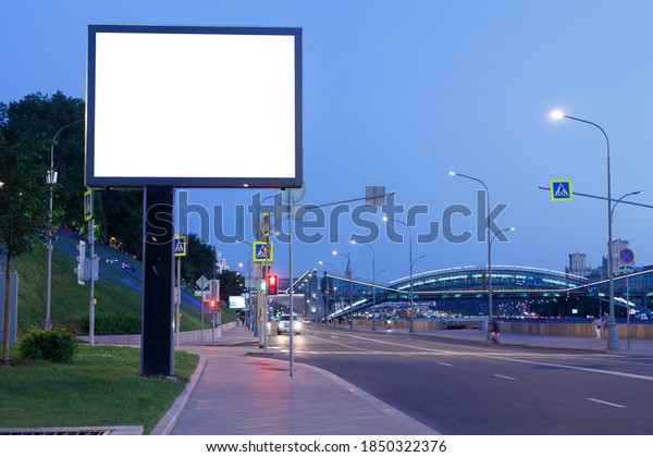 Big\
billboard on a pillar in the evening city, mock\
up.