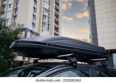 Big Black Box Of Luggage Rack On The Roof Of A Black Car. Travel And Transportation Accessories.