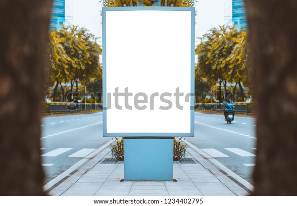 big blank billboard white LED screen vertical\
outstanding in city on pathway center between the road traffic for\
display advertisement text template promotion new brand at outdoor\
with green tree.