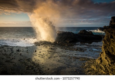 Big blow hole spraying ocean mist into the air in Hawaii on the Island of Oahu