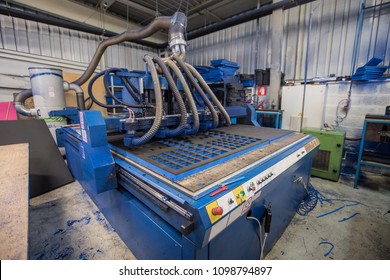 A big blue CNC machine is cutting holes on a foam material. Industrial interior. - Powered by Shutterstock