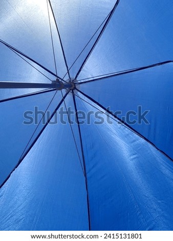 Big blue umbrella exposed to hot sunlight. Sparkling umbrella in afternoon. Business umbrella for outdoor activities