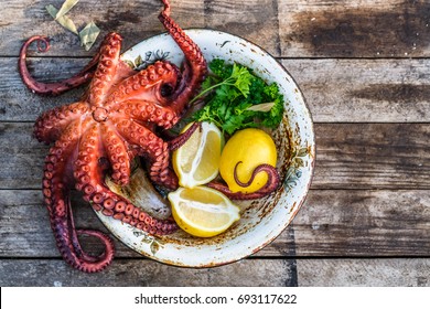 Big boiled octopus with lemon and parsley, rustic style, top view