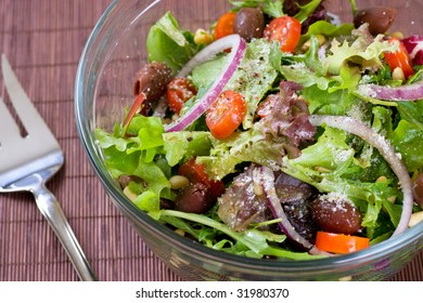 A Big Bowl Of Salad With A Serving Fork.